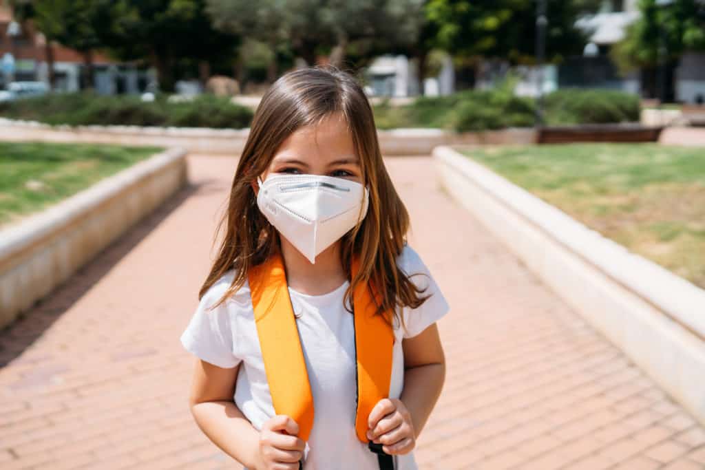 Schoolgirl in a backpack wearing a mask.